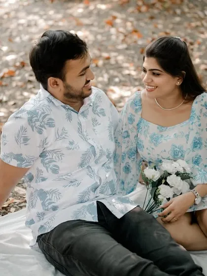 A simple, happy portrait of the couple sitting together on a picnic blanket. Their easy smiles and comfortable body language show their natural chemistry.