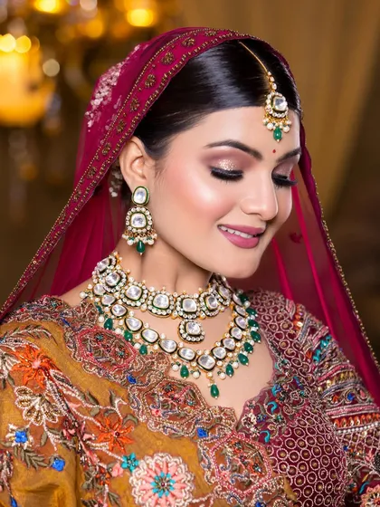 A smiling bride looking radiant in our two-layered green and white Kundan necklace set with a matching maang tikka.