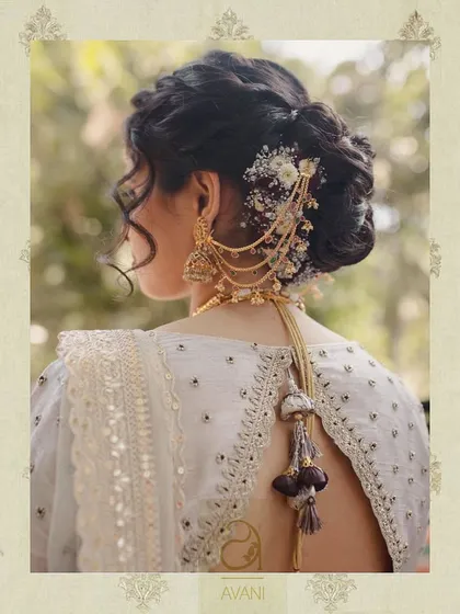 A close-up of a bride's hairstyle and the back of her blouse. The design features a sheer panel with delicate tassels and intricate embroidery, showing how every detail is considered.