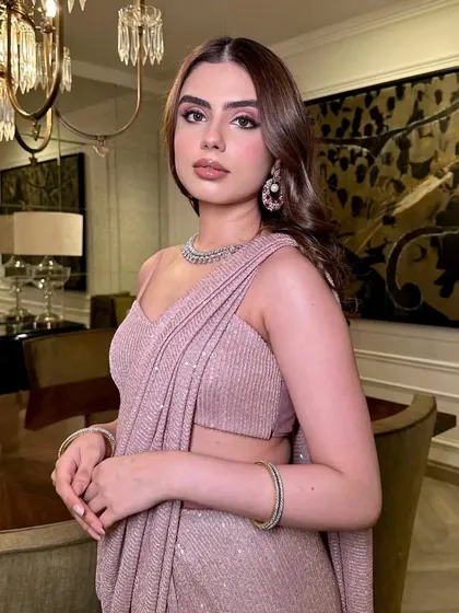 A picture-perfect soft glam look. The makeup is subtle yet impactful, with a focus on flawless skin and a nude lip, letting the glittery saree take center stage.