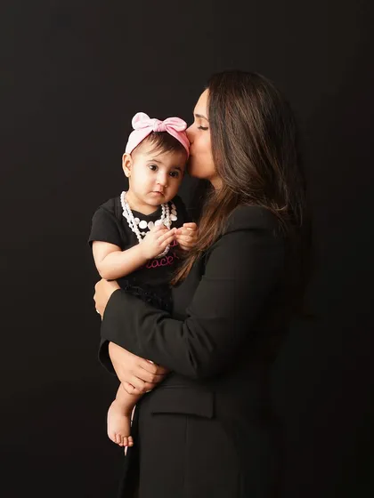 A mother places a gentle kiss on her daughter's head. This portrait is full of tenderness and the quiet love between a mother and her child.
