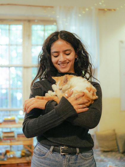 The pure joy of a kitten cuddle. A participant smiles, holding a sleeping ginger kitten close to her heart.