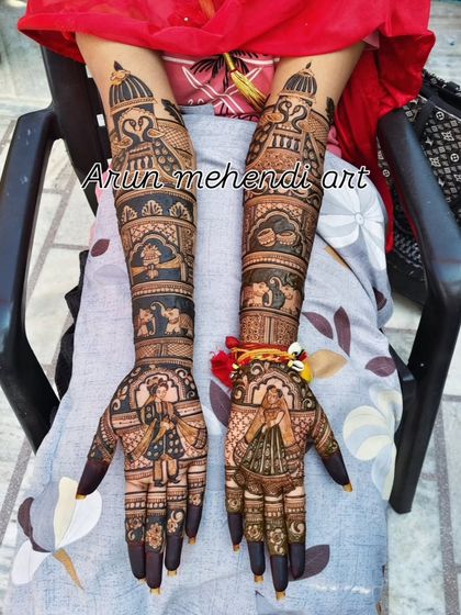 A classic bridal design with bride and groom portraits, peacocks, and elephants, covering the arms fully.