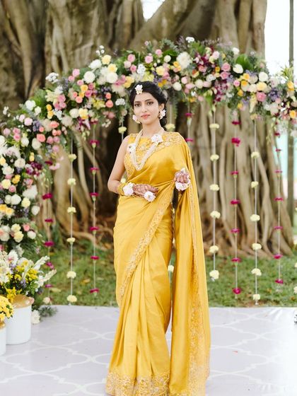 The beautiful bride at her Haldi ceremony, perfectly framed by the floral arch we designed. The decor was created to complement the natural surroundings and her elegant yellow saree.