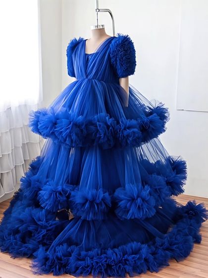 A full view of this magnificent royal blue ball gown. The multi-layered, ruffled skirt creates incredible volume, making it a perfect choice for a grand, fairytale-inspired photoshoot.