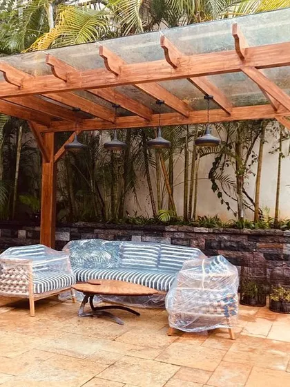 Craftsmanship is key in our hardscape projects. This custom-built wooden pergola with a glass roof provides a sheltered outdoor seating area, perfectly integrated with the surrounding garden and stone patio.
