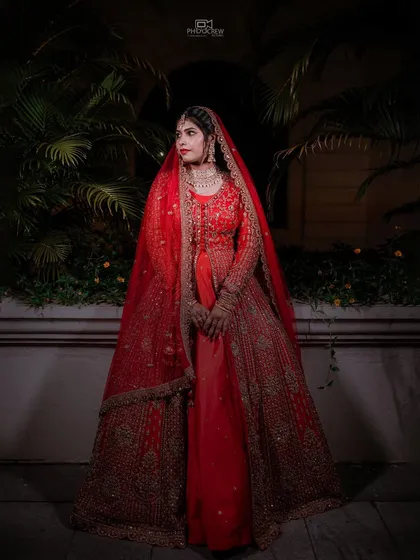 A full-length portrait of the bride in her magnificent red lehenga, showcasing its grandeur.