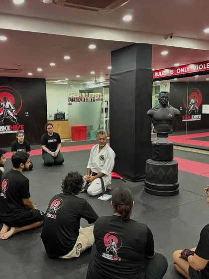 We don't just train together, we grow together. Students listen intently to a senior instructor, absorbing wisdom that goes beyond physical technique.