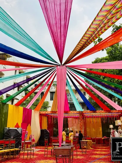 I love creating that perfect, festive 'shadi vala ghar' feel for Haldi and Mehndi functions. This outdoor setup features a canopy of vibrant, multi-colored drapes, creating a joyful and picturesque setting for your pre-wedding rituals.