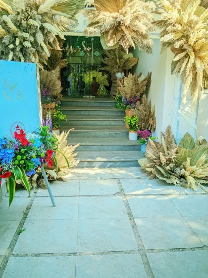 The entrance steps to a venue decorated with pampas grass and colorful flower arrangements for a rustic, bohemian-themed party.