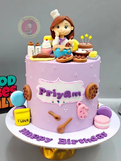 A full view of a baker-themed birthday cake. This one includes tiny fondant flour sacks, spoons, and oven mitts for a complete baking scene.