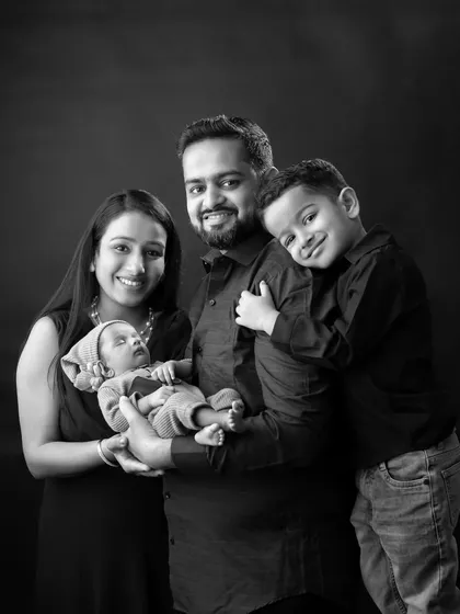 A classic black and white studio portrait of a family of four, welcoming their newest newborn member.