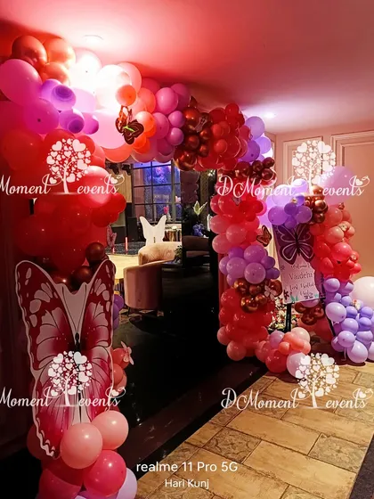 A vibrant entrance arch for a butterfly party, using a bold color palette of red, pink, and purple balloons to create a dramatic effect.