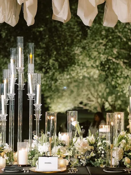 A tablescape glowing with dozens of candles in tall glass holders, creating a forest of light that is both dramatic and romantic.