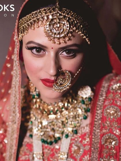 A direct and confident gaze from the bride. The makeup features a classic combination of a winged liner, bold red lip, and perfectly sculpted brows, creating a look that is both strong and beautiful.