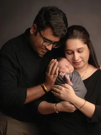 A warm family embrace. This pose, with both parents holding their newborn close, creates a feeling of love, safety, and togetherness.