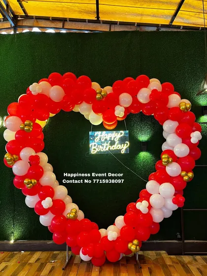 A large, heart-shaped balloon arch is a bold and romantic statement piece. I built this one with red and white balloons against a green wall, complete with a neon sign, perfect for anniversaries or proposals.