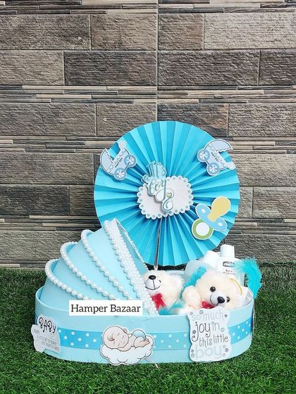A cute baby pram hamper in blue, filled with soft toys and other goodies.