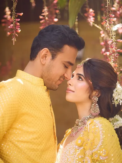 A romantic moment between the couple at their Haldi. Her makeup is soft and natural, letting her happiness shine through.