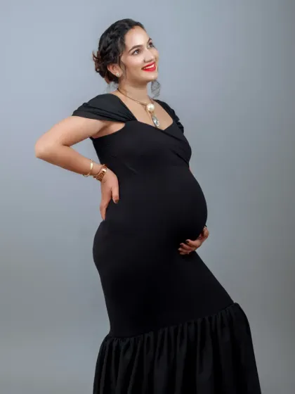 A classic and powerful portrait in a black mermaid gown. The simple grey backdrop makes the mother-to-be's joyful expression and beautiful form the center of attention.