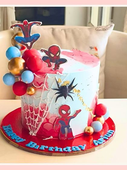 A web-slinging Spider-Man cake with red and blue accents, spiderwebs, and character toppers for a superhero-themed birthday.