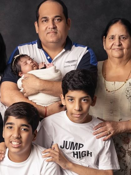 Three generations united in one frame. The grandmother's gentle hold and the older siblings' proud smiles create a powerful story of family continuity and love.