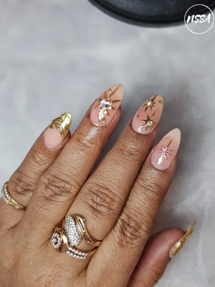 A stunning set of celestial-themed nails with gold leaf and star accents, done by a student. This shows their ability to create a cohesive and elegant full set.