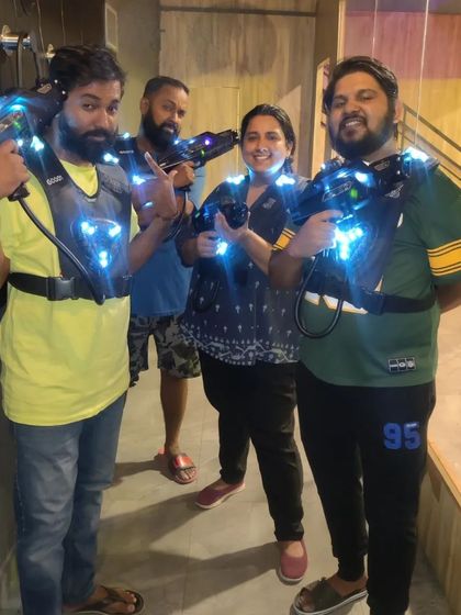A group of friends gives a thumbs up, ready for their laser tag adventure.