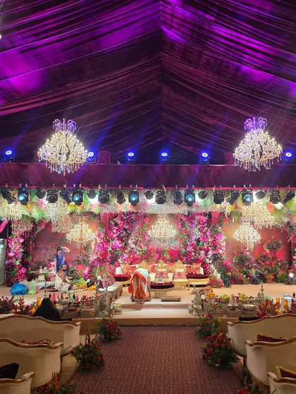 A full view of the grand floral wedding stage and the guest seating area. The purple uplighting and extensive floral work create a cohesive and luxurious ambiance throughout the venue.