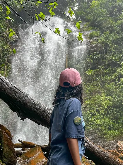 A trekker gazes at a waterfall in the dense forest of Kodachadri.