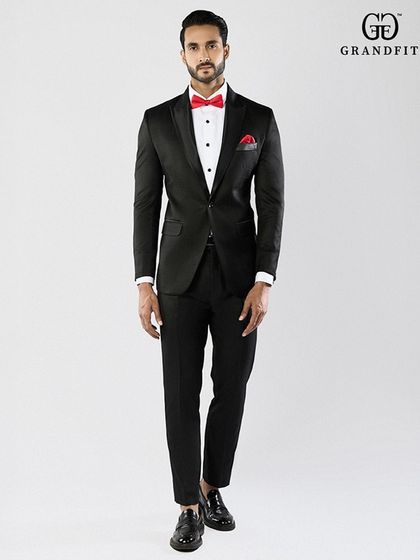 A touch of color can personalize a classic look. Here, a vibrant red bow tie and matching pocket square add a confident and modern flair to the traditional black tuxedo.