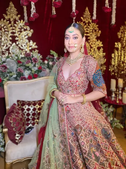 A full-length shot capturing the bride's radiant smile and majestic presence. The makeup is crafted to stand out beautifully against the opulent backdrop and the richly detailed bridal attire.