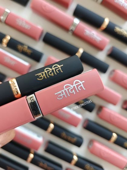 Personalized L'Oréal lipsticks for 'Aditi'. The contrast between the gold on black and silver on pink casings creates a stunning visual effect.