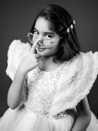 A sassy and fun black and white portrait from a birthday session. The combination of a sparkly dress, angel wings, and heart-shaped glasses shows her playful side. I love capturing these expressive moments that truly reflect a child's character.