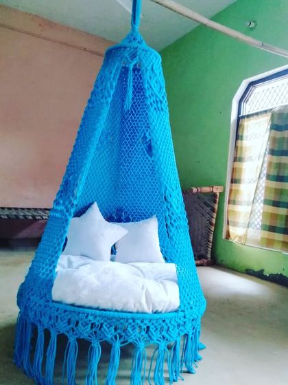A sky-blue single seater swing with white star pillows. It's a fun and comfortable addition to a kid's room or a playful corner of your home.