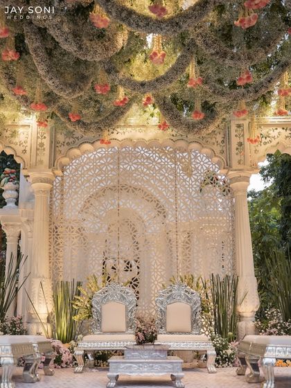 A closer look at the mandap seating, featuring ornate silver chairs against a backdrop of intricate white latticework. The floral canopy above added a layer of softness and romance to the regal design.