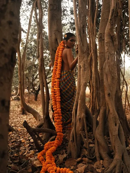 A wide shot that emphasizes the dramatic length of the marigold hair extension, weaving a story of folklore and myth within the forest landscape.