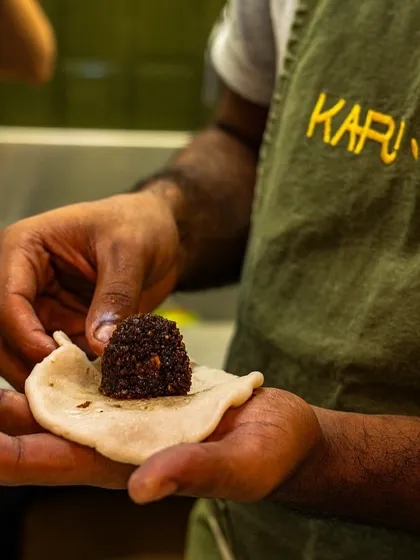 A behind-the-scenes shot of a chef at Kari Apla carefully preparing a traditional dish for their Onam sadhya, showing the hands-on care involved.