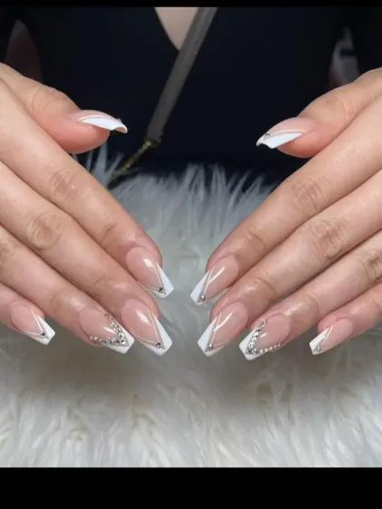 A modern V-French design on long coffin nails. This sharp, angular style is accented with rhinestones at the base for a touch of glamour.
