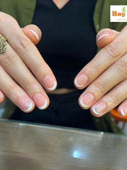 Chic and classy nails for any occasion. This photo shows a beautiful French manicure on short, natural nails, with one accent nail featuring a subtle silver glitter overlay.