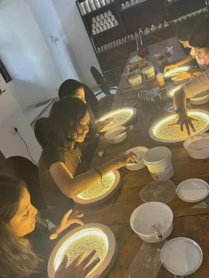 Students from a local school deeply engaged in creating their own textured moon lamps. The focused, low-light setting helps bring out the glowing details of their artwork.