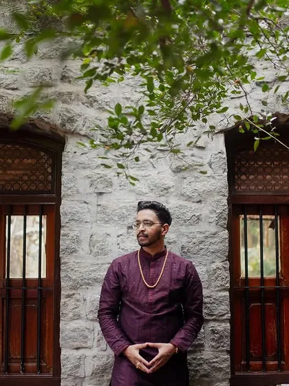 A portrait of the groom against a rustic stone wall and antique wooden windows, showcasing a masculine and timeless look.