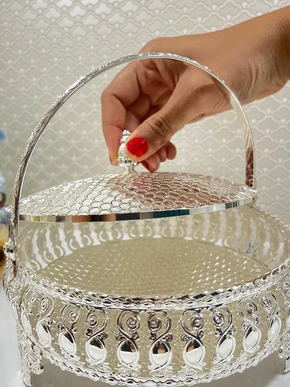 Perfect for presenting sweets or wedding favors, this exquisite oval silver basket features a hammered lid and ornate detailing, adding sophistication to any celebration.