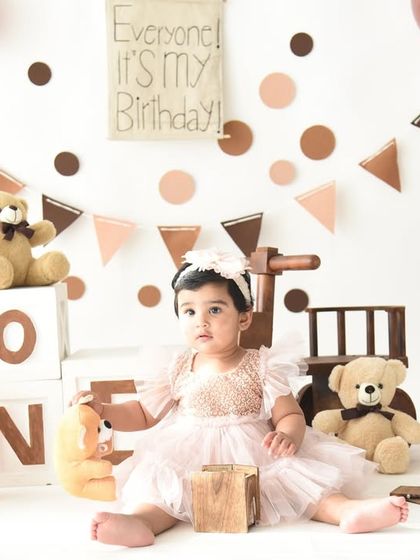 Posed and ready for her first birthday celebration. This shot shows off her beautiful dress and the adorable, classic teddy bear theme we created in the studio.