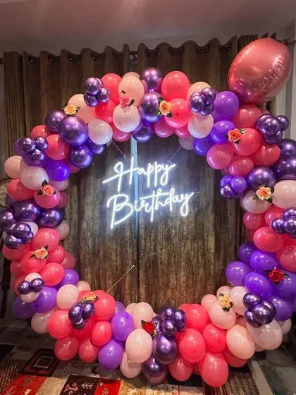 A full balloon ring in vibrant shades of purple and pink. This decoration is perfect for adding a pop of color to any birthday party, complete with a central neon sign.