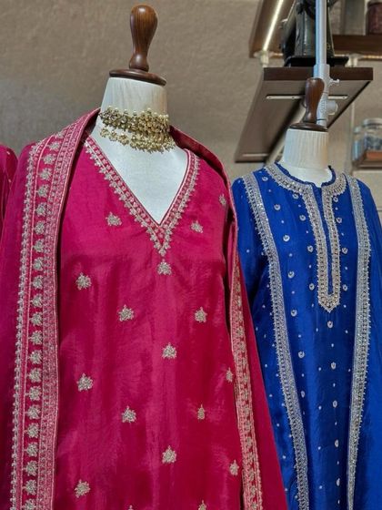 A beautiful display of festive suits in fuchsia pink and royal blue, featuring intricate silver embroidery.