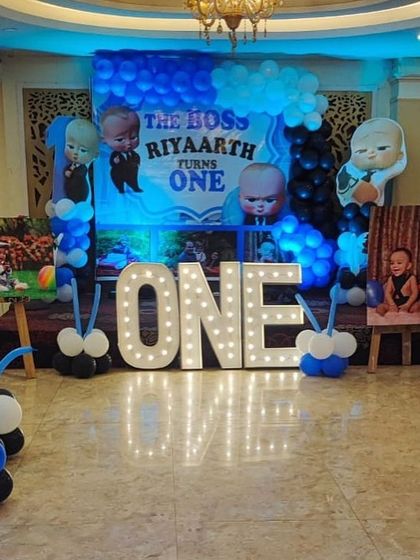 The main stage for a Boss Baby first birthday, featuring a large 'ONE' marquee sign and character cutouts.