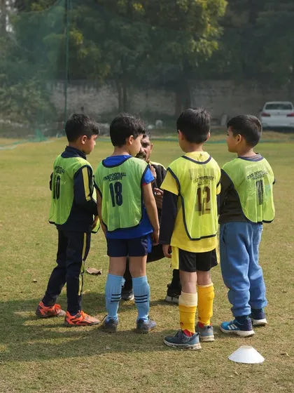 A coach talking to his players in a huddle. We foster a sense of community and belonging from the first kick to the final whistle.