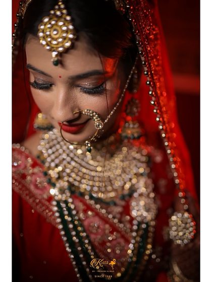 A beautiful portrait of a bride looking down, her face softly lit against a red background.