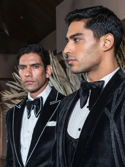 A study in monochrome sophistication. This image showcases two of our bespoke velvet tuxedos, one featuring delicate crystal outlining on the lapels and the other a classic three-piece construction, offering distinct options for formal evening wear.